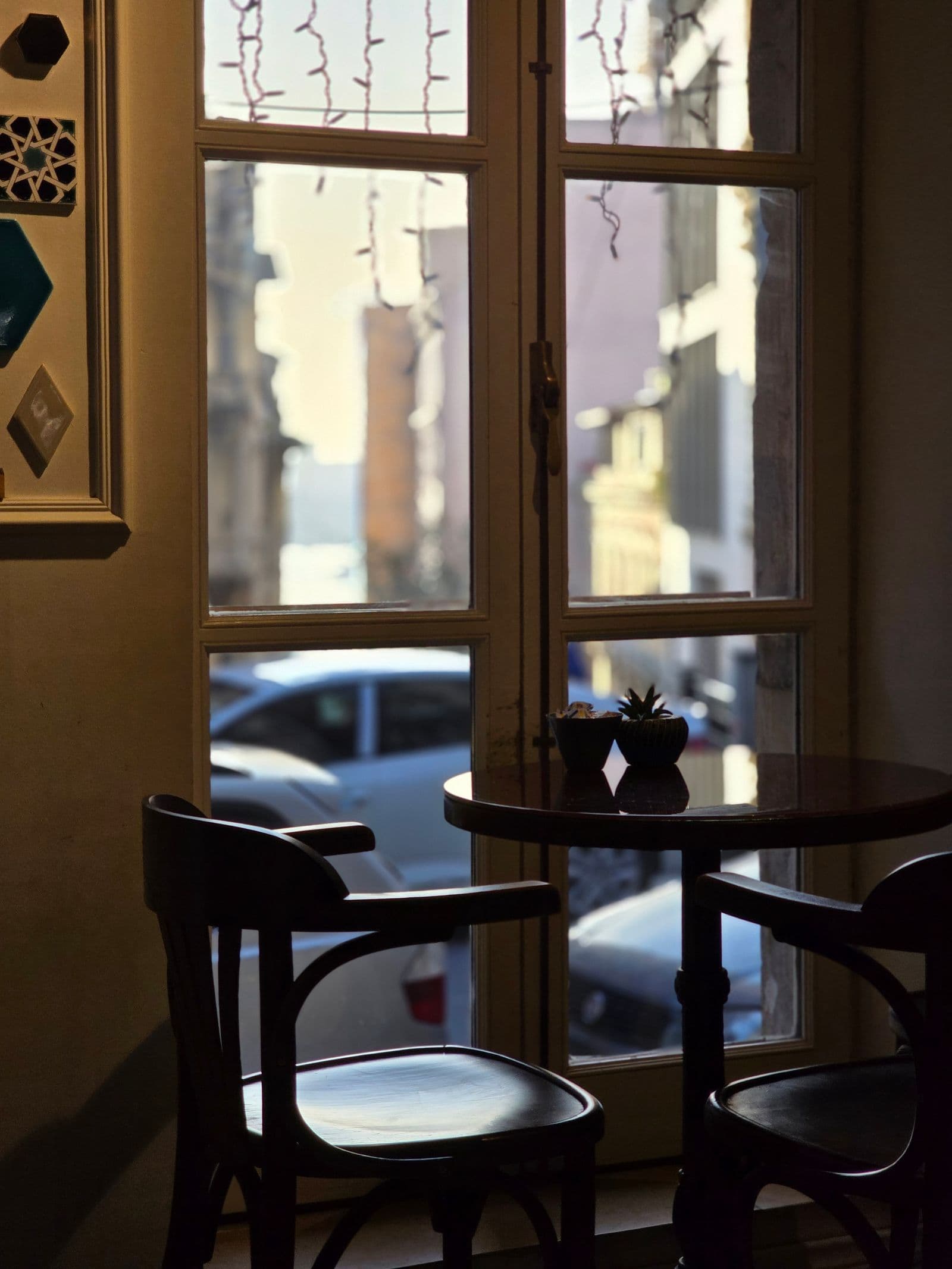 A quiet cafe table and chairs beside a sunlit window