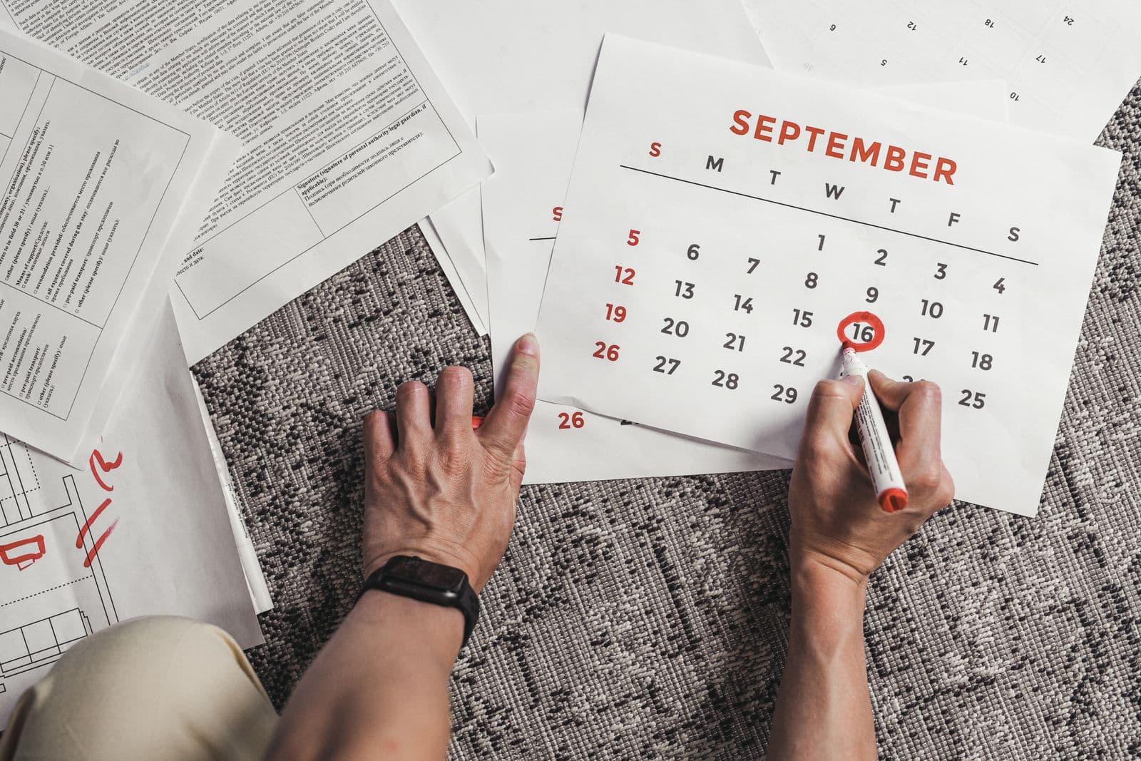 Hands holding a calendar page with a date circled in red