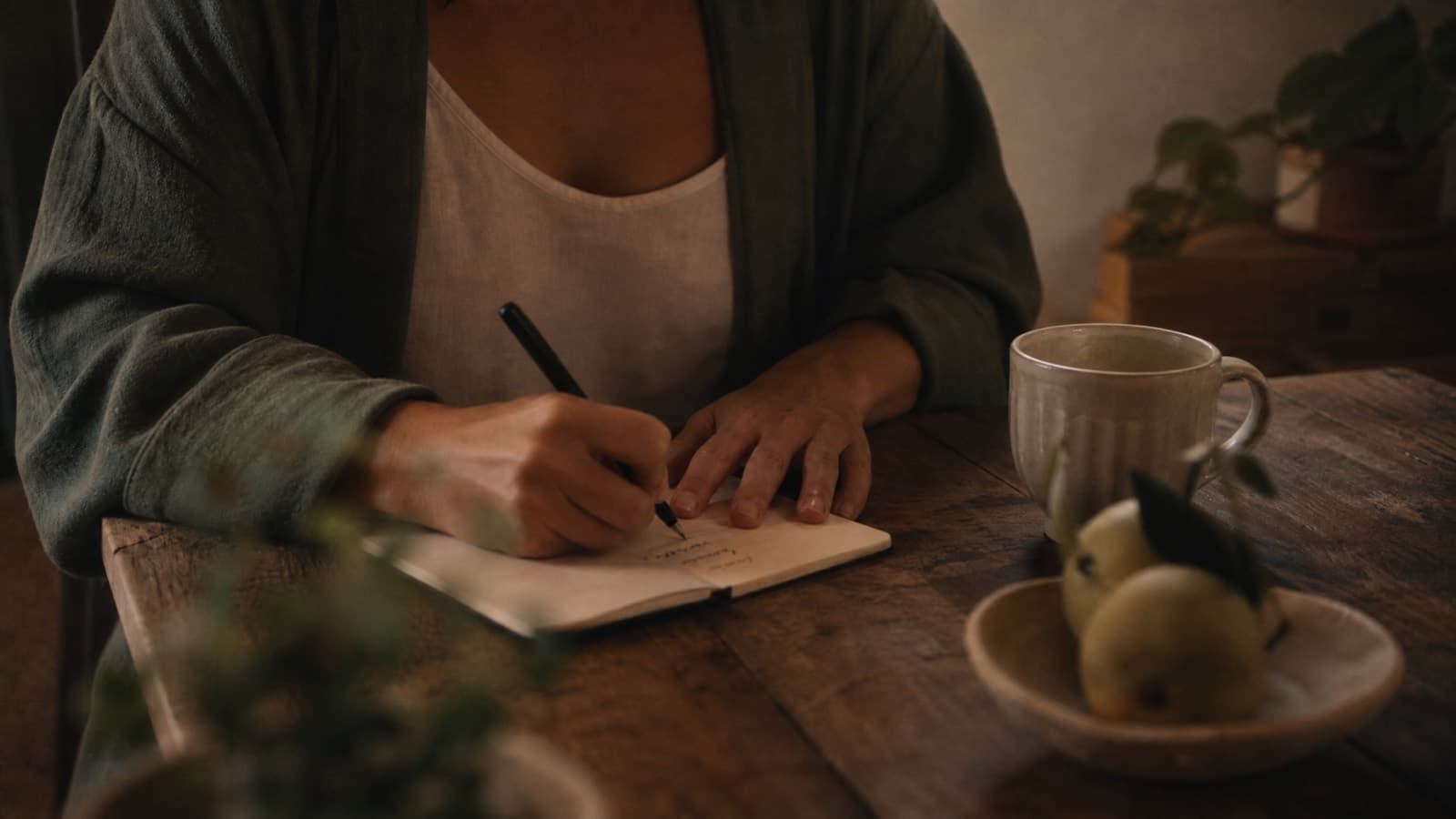 Someone writing by hand in a small notebook at dusk